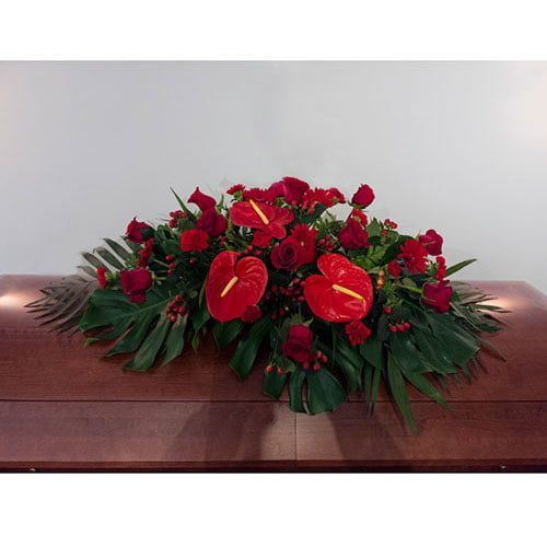 Coussin cercueil composé de roses rouges, d’anthurium rouge et de verdure